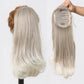 Blonde hair extension on a mannequin head with packaging held by a hand.