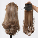 Brown hair extensions shown on a mannequin head and held by a hand against a white background.