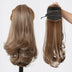 Brown hair extensions shown on a mannequin head and held by a hand against a white background.