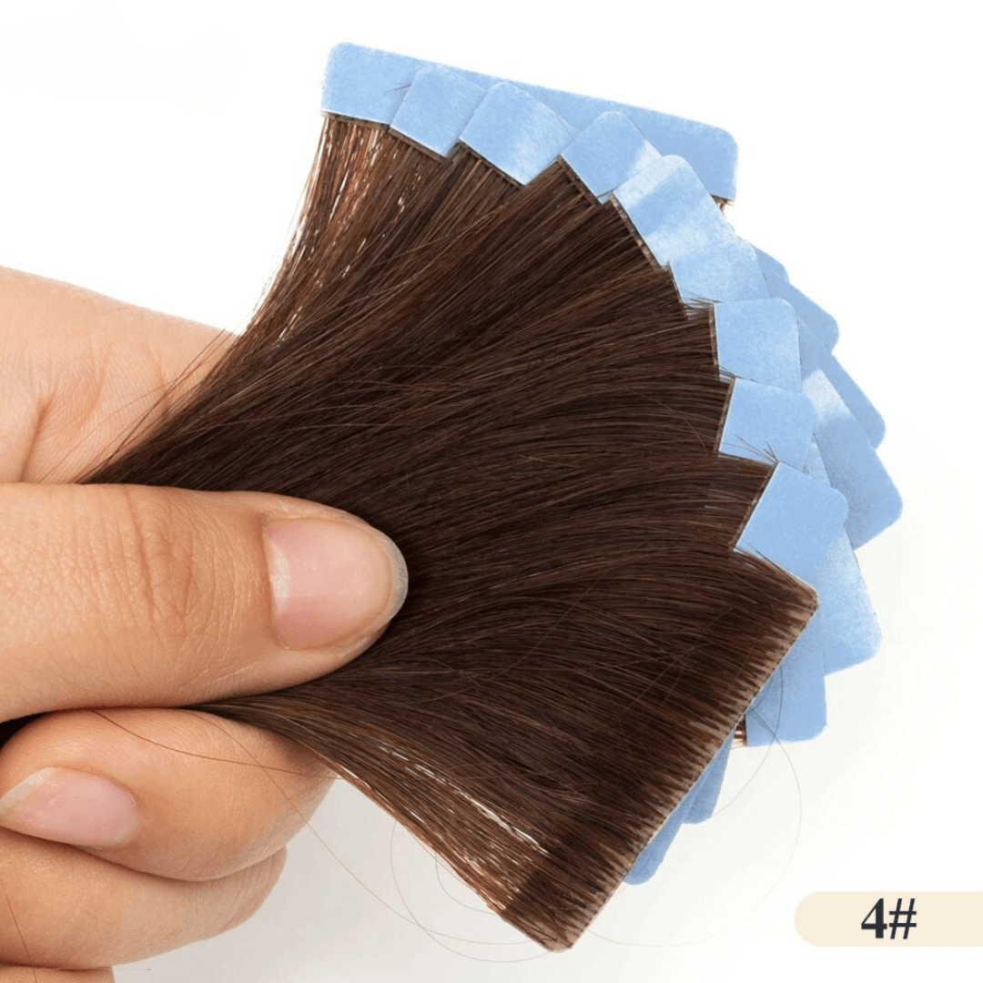 Hand holding a sample of brown hair extensions with a white background