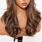 Model wearing honey brown bang wig with face-framing blonde highlights and soft waves