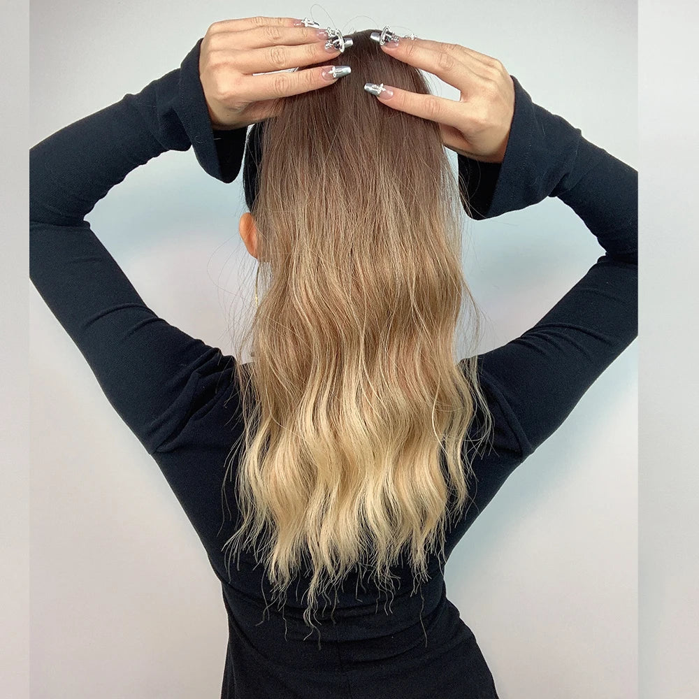 Person holding a blonde hair extension against a plain background