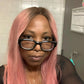 Person with pink hair and glasses in a bathroom setting