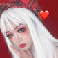 Person with white wig and red makeup against a red background with a heart symbol