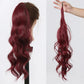 Red hair extension worn by a person and held in a hand on a white background