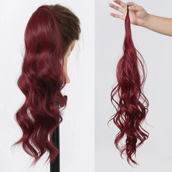 Red hair extension worn by a person and held in a hand on a white background