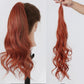 Reddish-brown hair ponytail extension on a mannequin head and held by a hand against a white background.