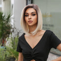 Woman with a blonde bob wig wearing a black top outdoors.