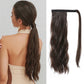 Woman with long wavy hair in a ponytail extension next to a hair extension on a white background