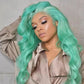 Woman with mint color wig wearing a beige outfit against a neutral background