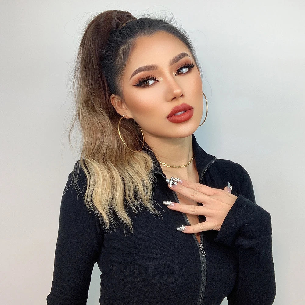 Woman with styled ponytail hair extension and makeup wearing a black outfit against a plain background